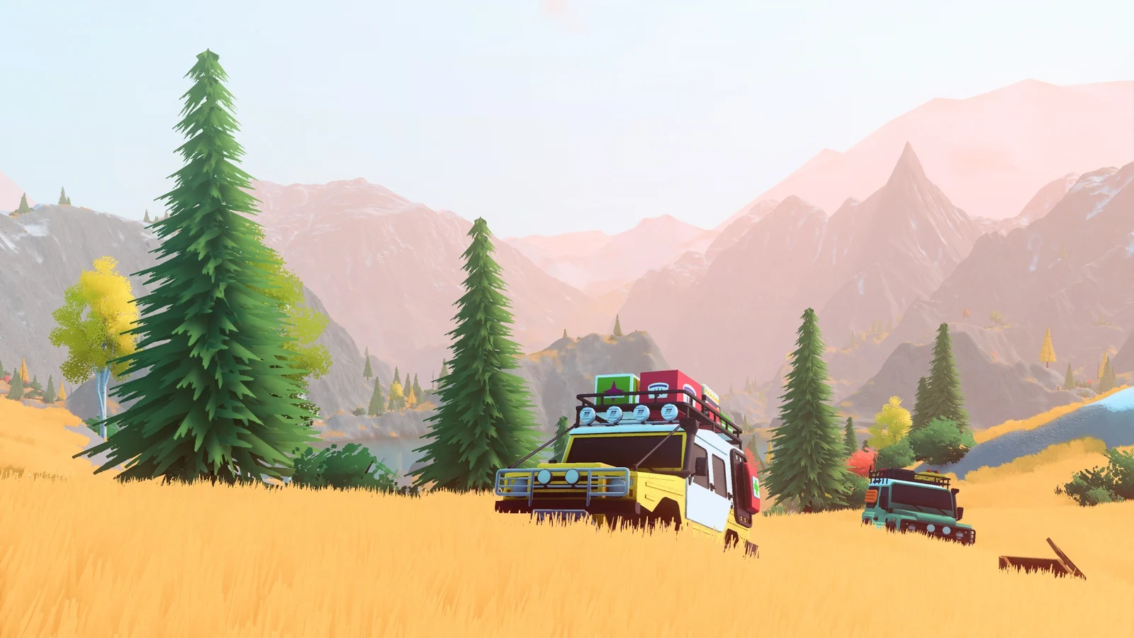 Off-road vehicles in golden grass, with conifers and layered mountains beyond.